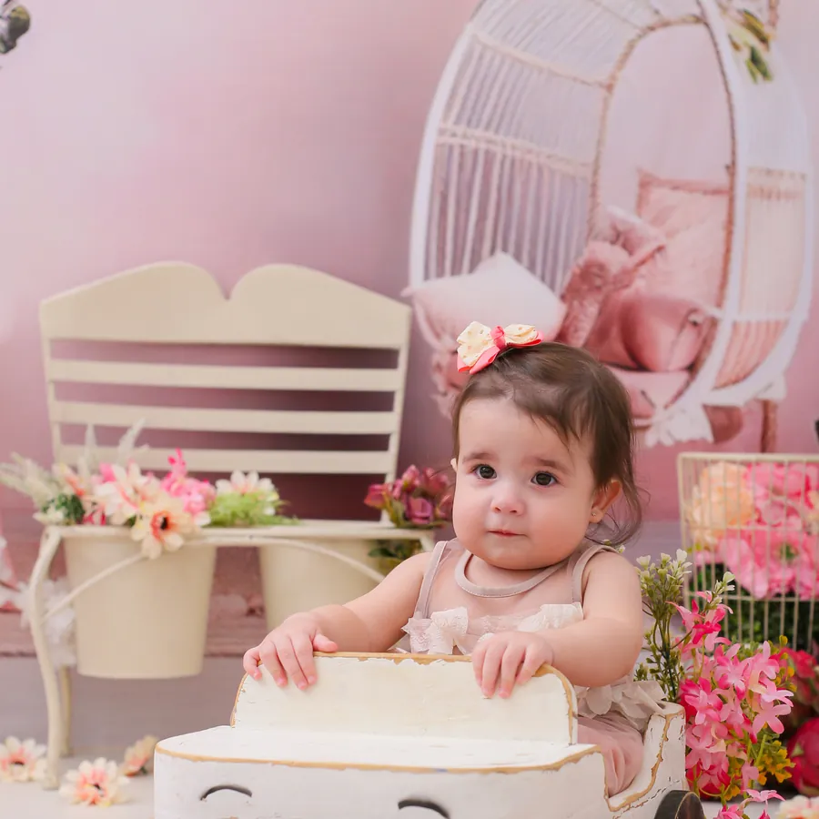 Olívia brincando com o bolo em cenário rosa