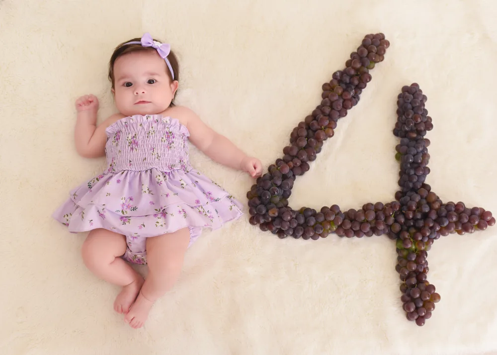 Olívia aos 4 meses ao lado de um número 4 feito de uvas