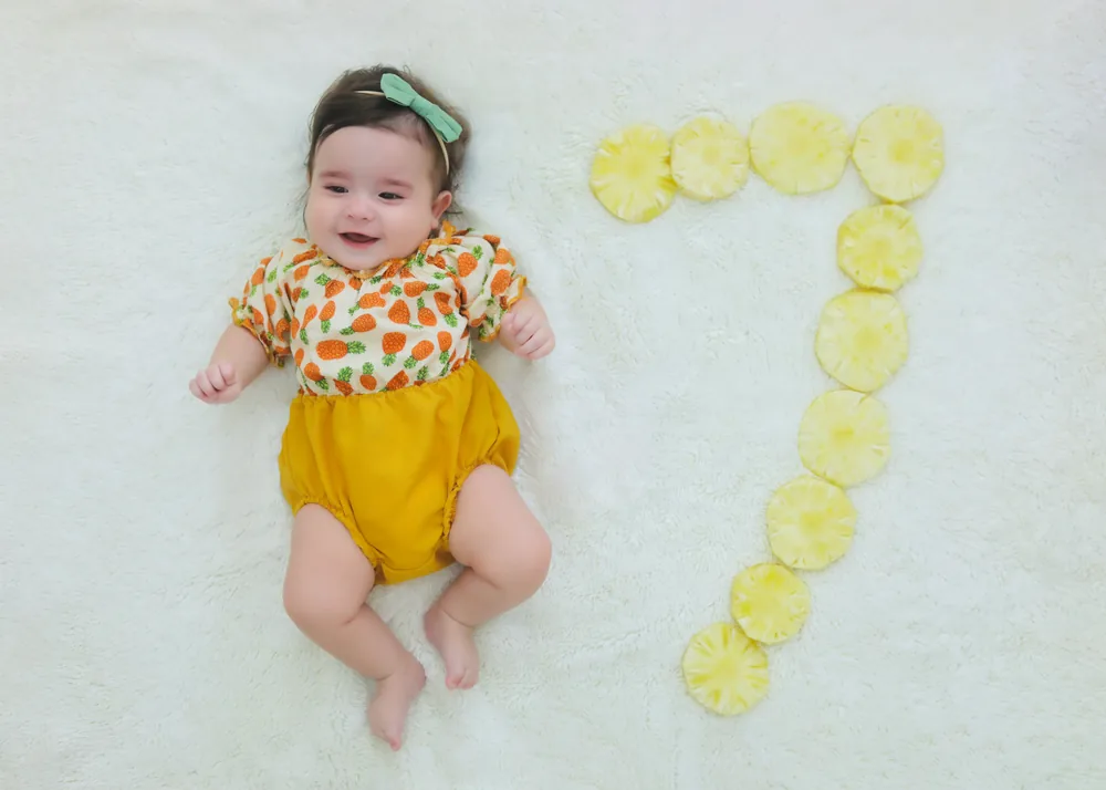 Olívia aos 7 meses ao lado de um número 7 feito de rodelas de abacaxi