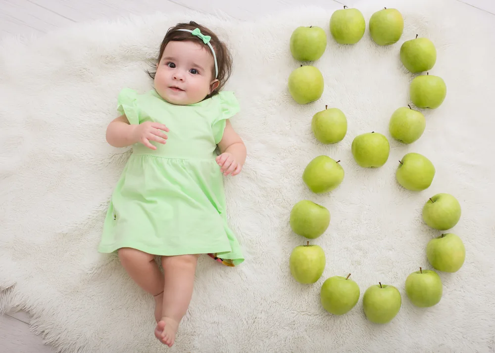 Olívia aos 8 meses ao lado de um número 8 feito de maçãs verdes