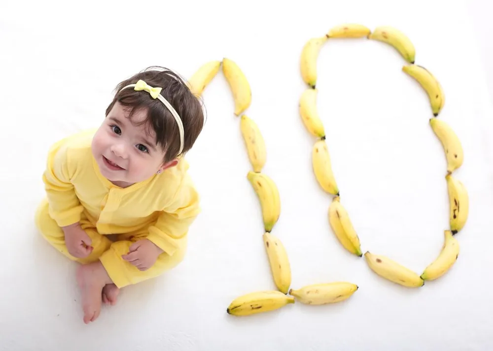 Olívia aos 10 meses ao lado de um número 10 feito de bananas